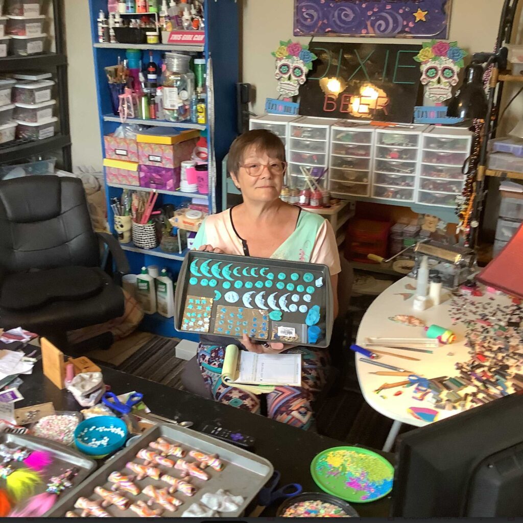 Jeanette Meyer in her New Orleans Studio holding a bakers pan spread with polymer clay figurines ready to be baked.